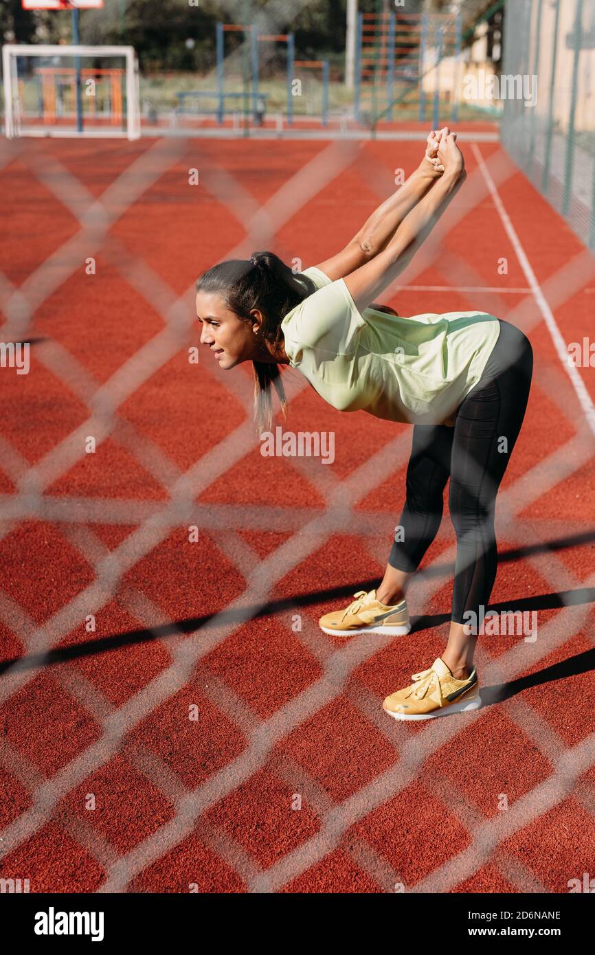 Fit and healthy female stretching arms at sport ground Stock Photo