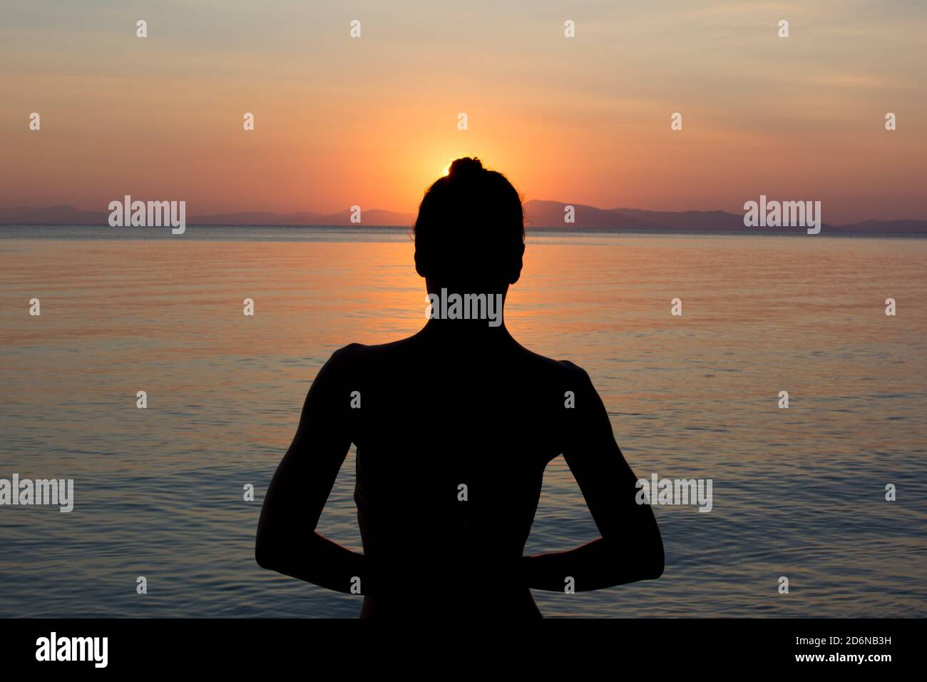 Beautiful Woman Sihlouette in Yoga Pose in front of Sunset Stock Photo