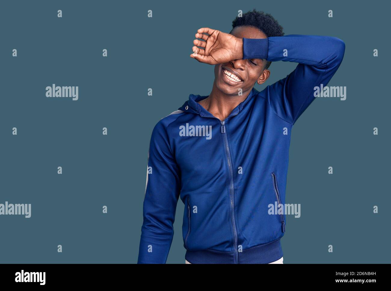 Young african american man wearing sportswear covering eyes with arm ...