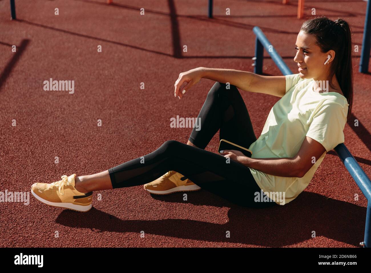 Relaxed woman in sportswear sitting on ground with mobile Stock Photo
