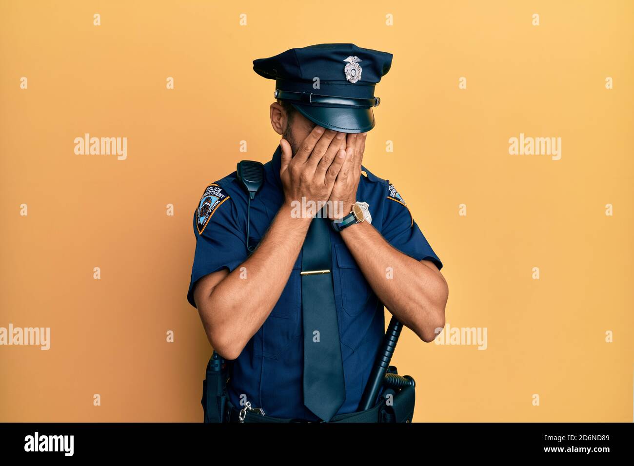 Handsome hispanic man wearing police uniform with sad expression covering face with hands while crying. depression concept. Stock Photo