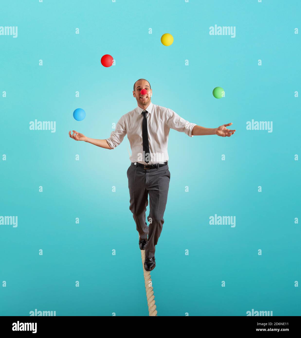 Worry man in balance walking on a rope overand acts like a juggler Stock Photo