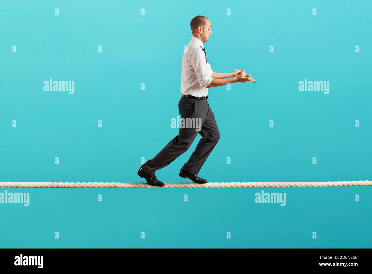 Worry man in balance walking on a rope Stock Photo
