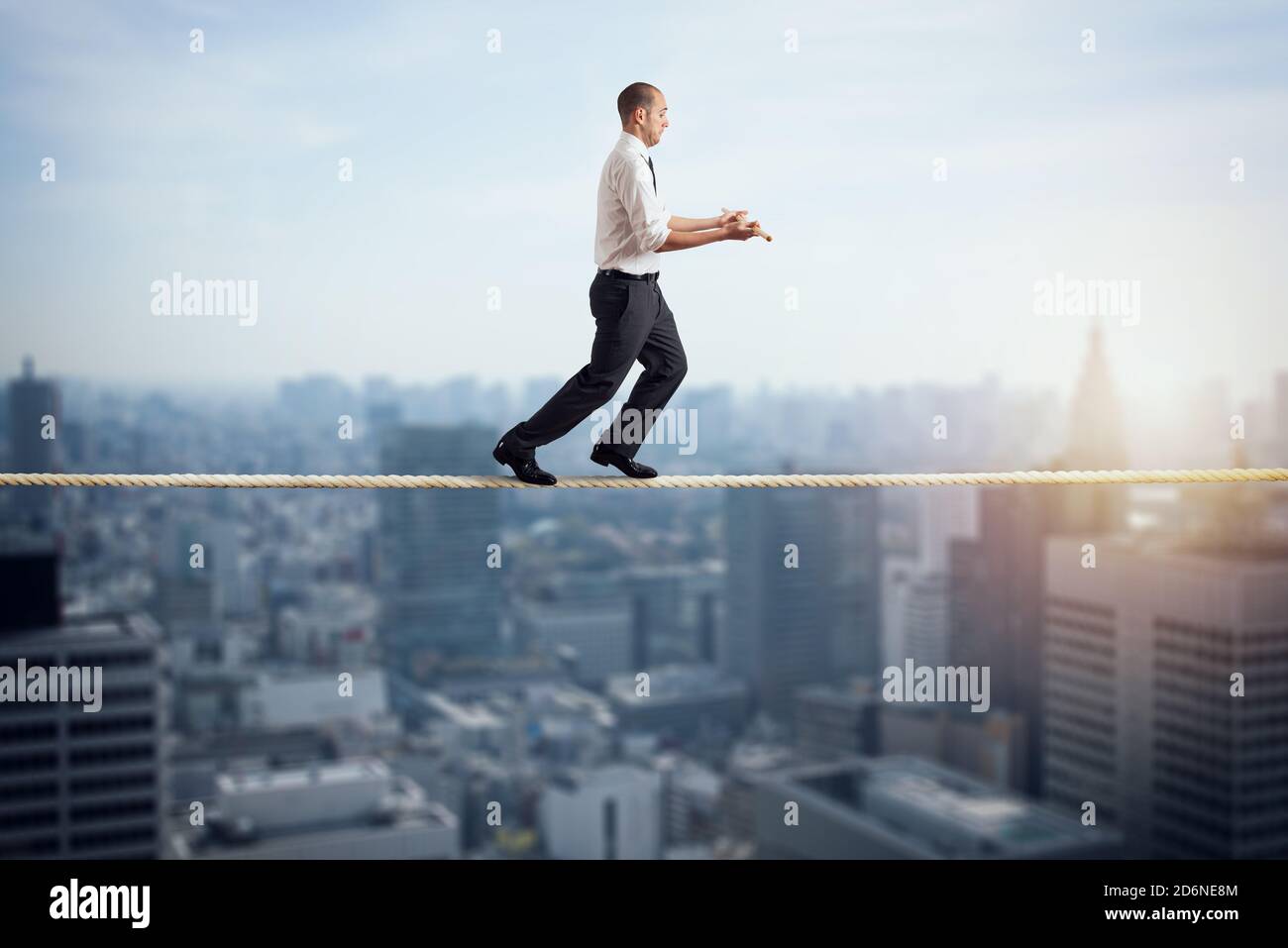 Worry man in balance walking on a rope over a city Stock Photo