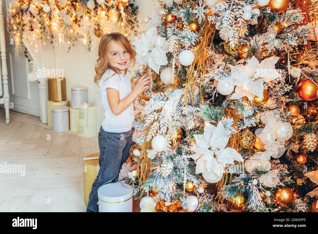 Dectrorting Little Tree Little girl decorating Christmas tree on Christmas eve at home. Young ...
