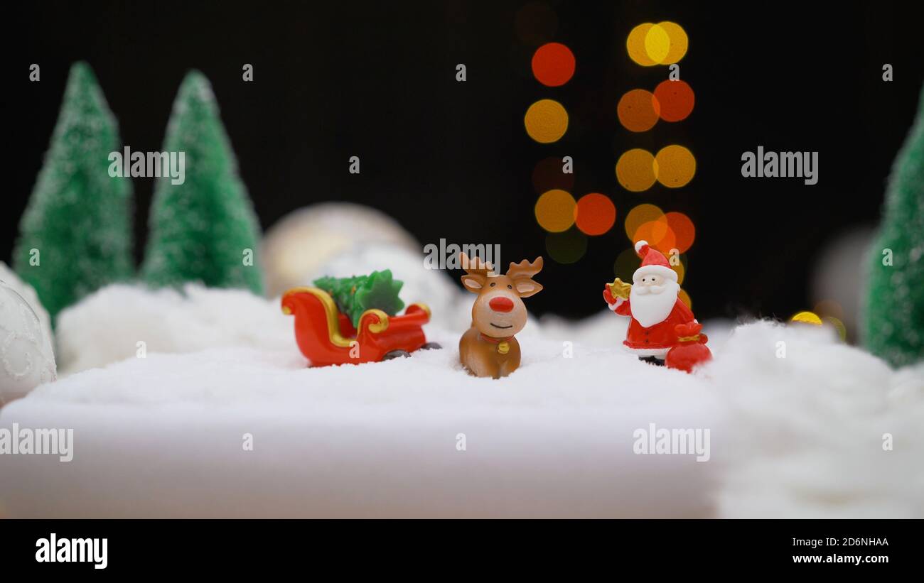Toy Santa Claus and a bag with Christmas gifts on the background of a Christmas tree. Toy santa claus with a bag of gifts. Stock Photo