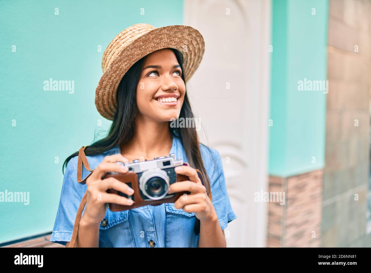 Young latin tourist girl on vacation smiling happy using vintage camera ...