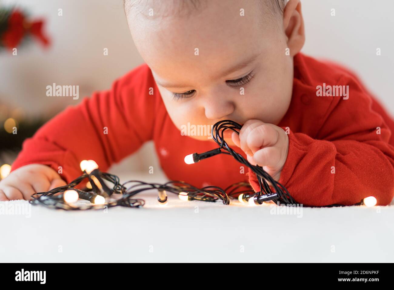 merry christmas and happy new year, infants, childhood, holidays concept - close-up 6 month old newborn baby in red clothes on his tummy crawls with Stock Photo