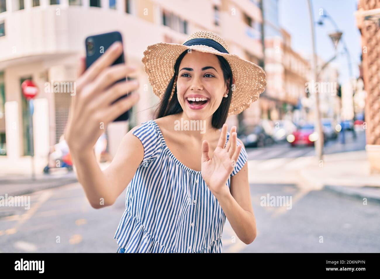 Young latin tourist girl on vacation smiling happy doing video call ...