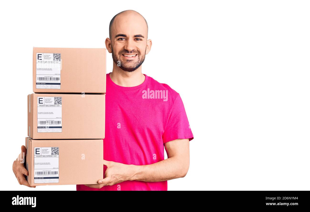 Young handsome man holding delivery package looking positive and happy ...
