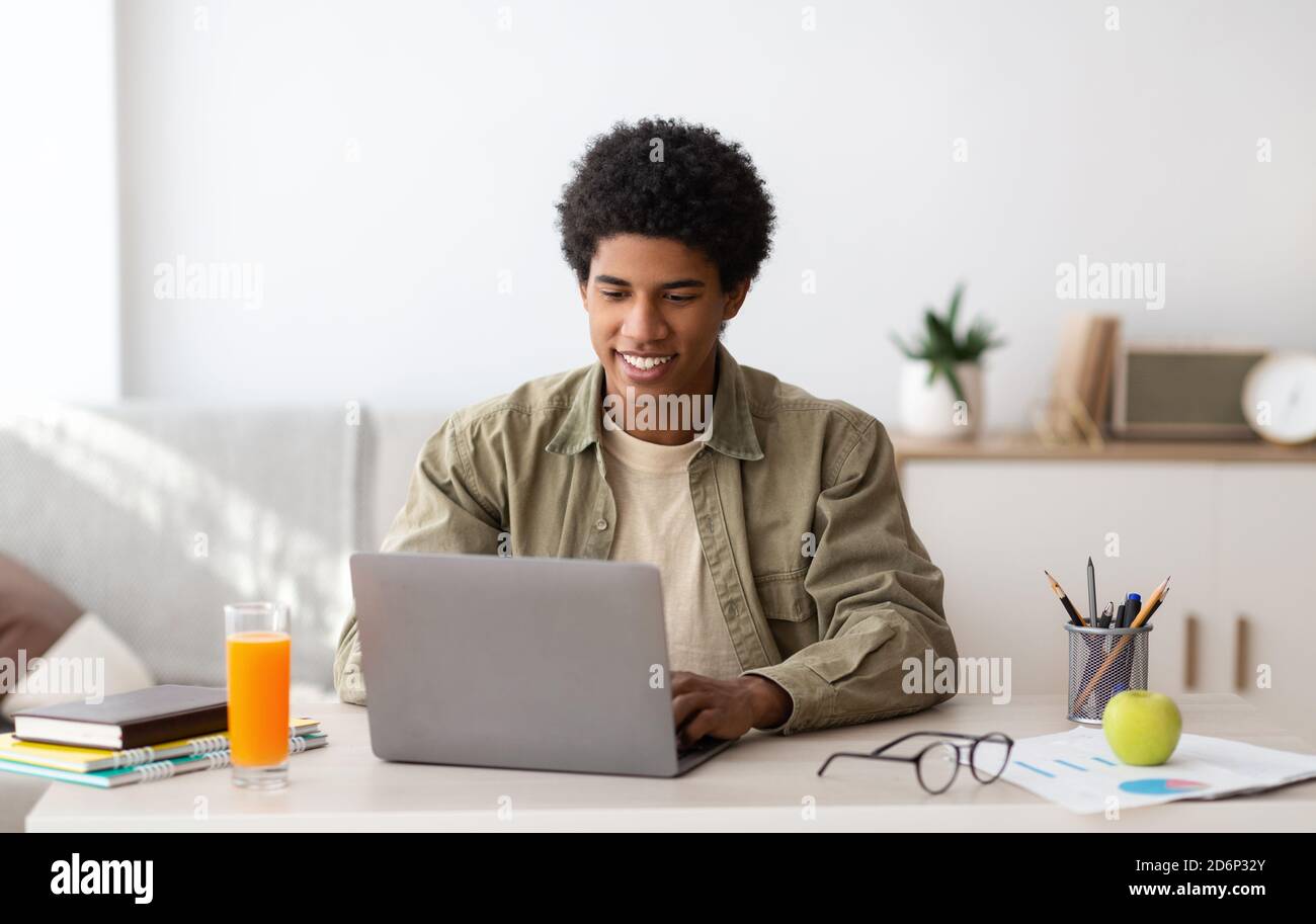 E-learning concept. African American teenager studying online on laptop computer at home Stock Photo