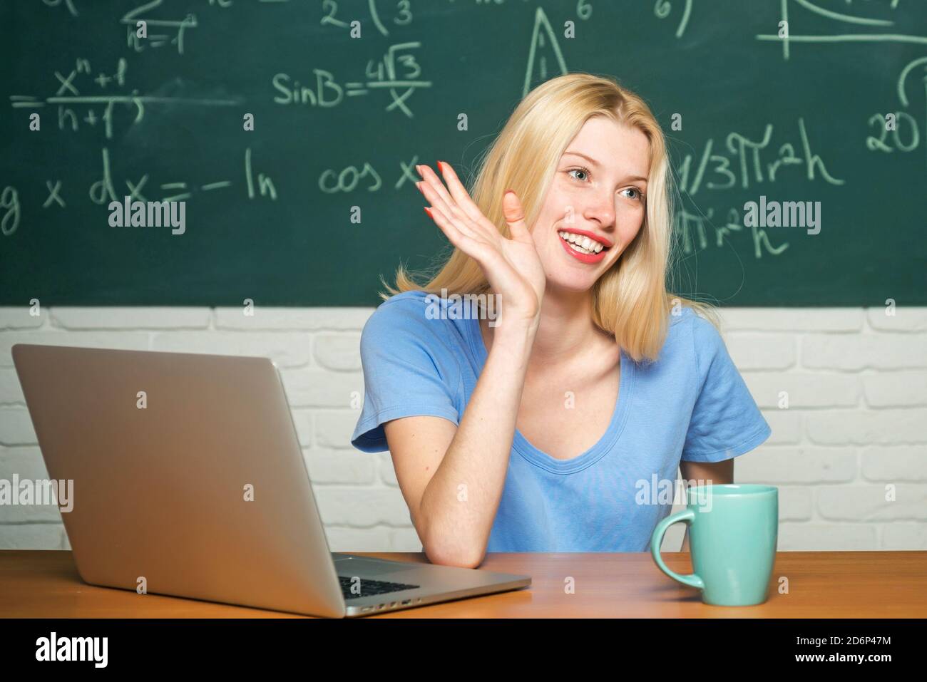 Happy student. Woman working on laptop computer over chalkboard