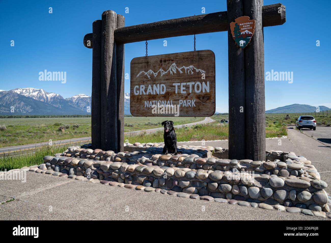 Jackson, Wyoming - June 27, 2020: A black labrador retreiver dog poses at the Grand Teton National Park sign Stock Photo