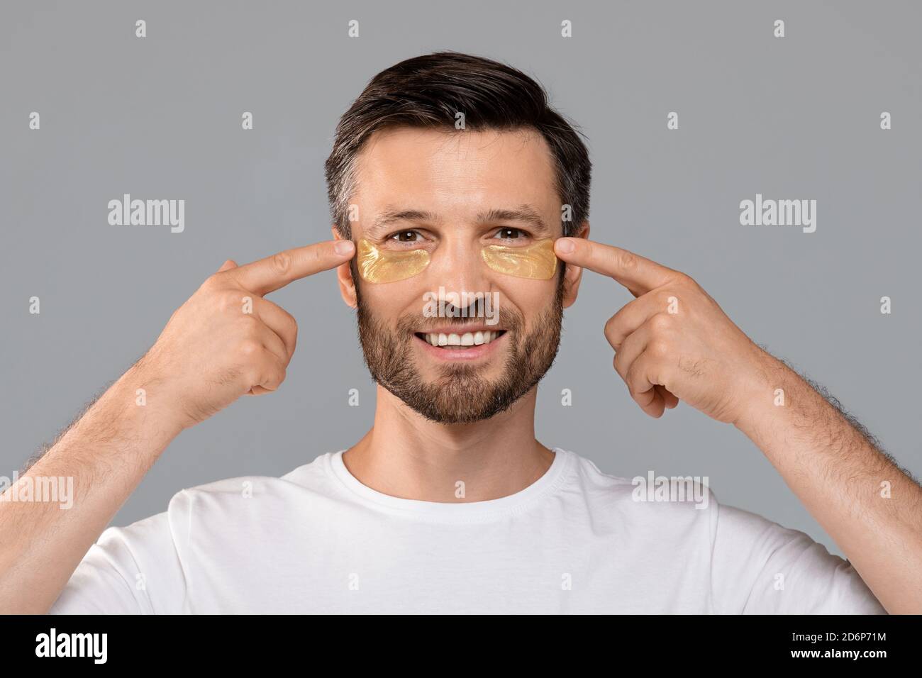 Smiling attractive man putting eye patches on his face Stock Photo Alamy