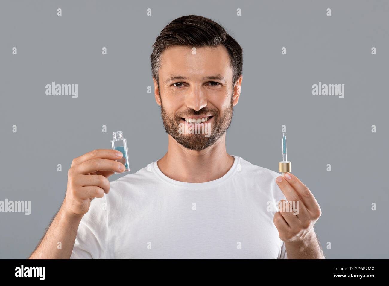 Middle-aged good looking man holding bottle with serum Stock Photo