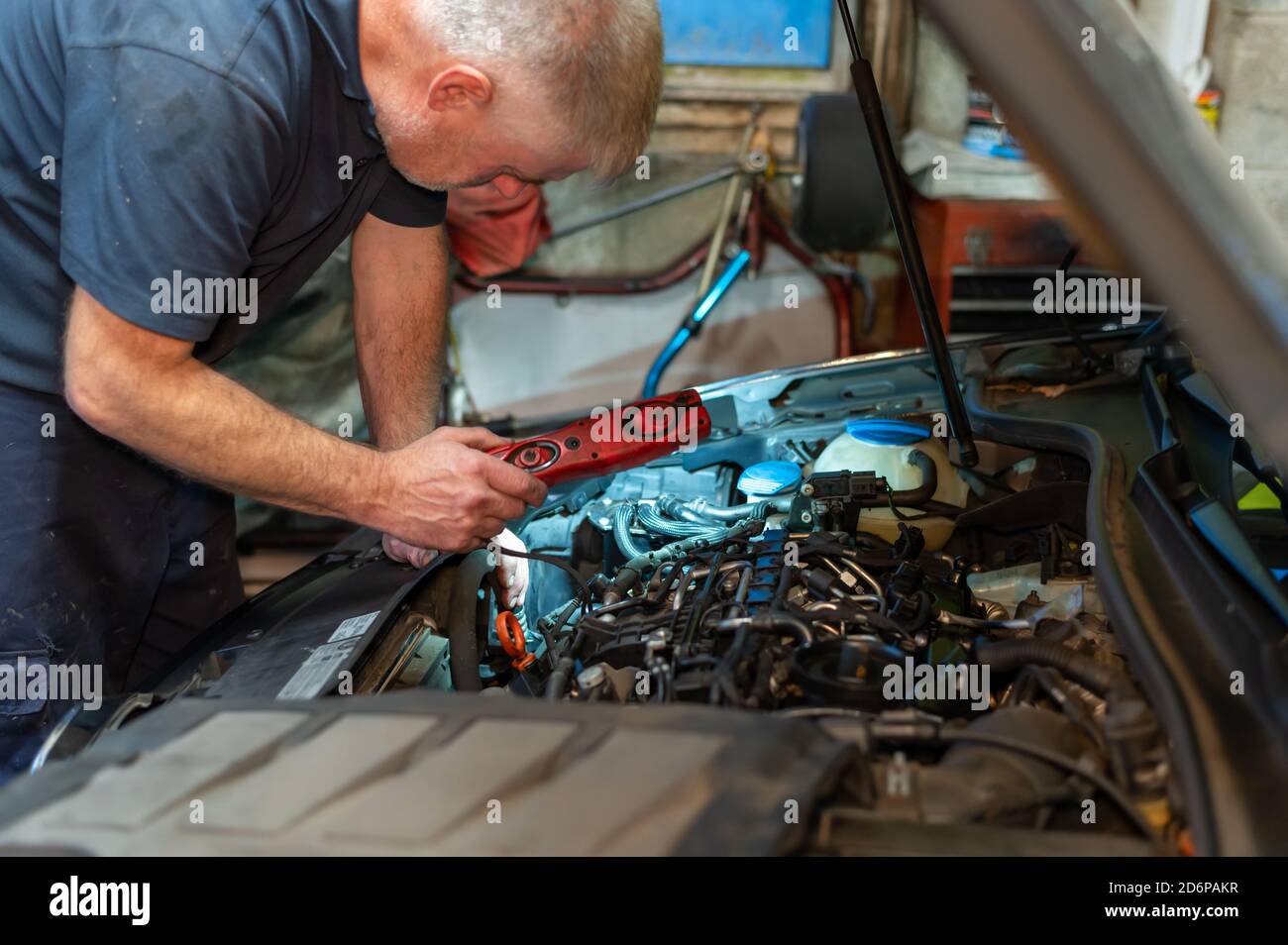 Senior Mechanic working on engine bay repairing a oil leak in home
