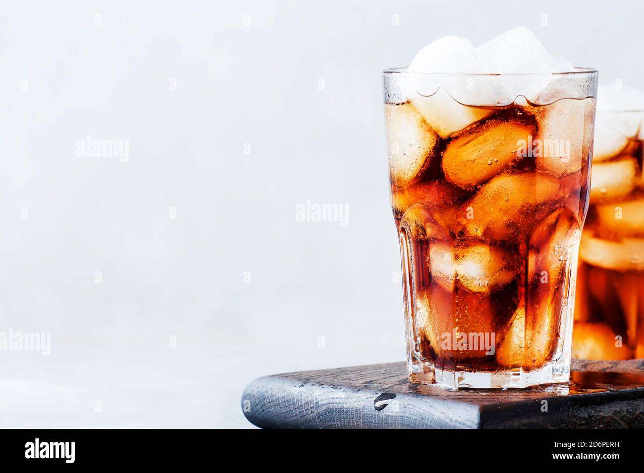 Alcoholic cocktail of rum-cola with ice, gray background, selective focus Stock Photo