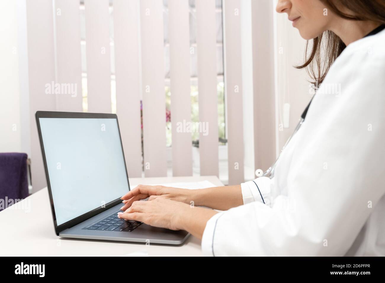 Close-up view on female doctor using laptop computer with mockup. Stock Photo