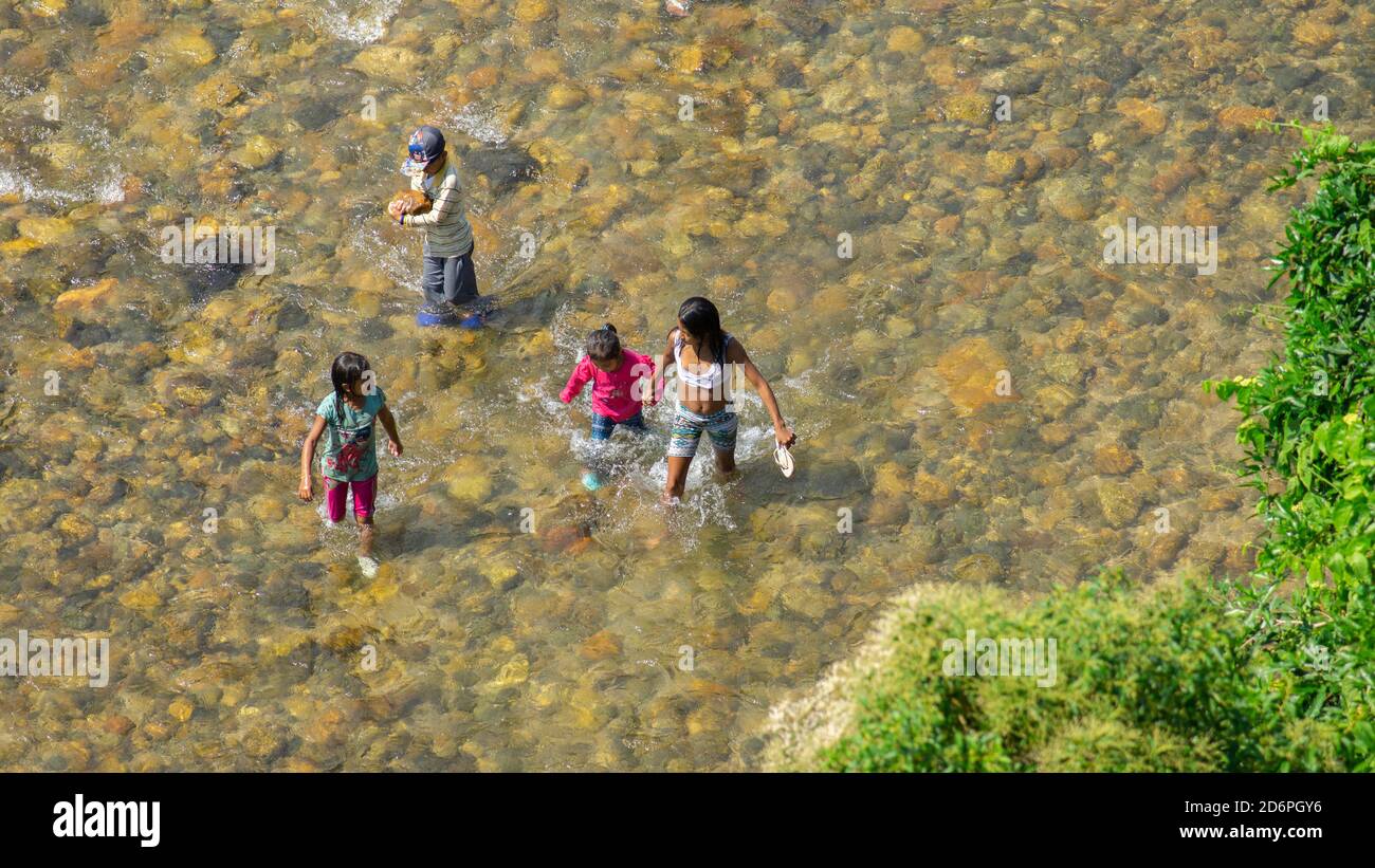 Tena, Napo / Ecuador - October 10 2020: Family bathing in the Napo river during the day in the city of Tena seen from above Stock Photo