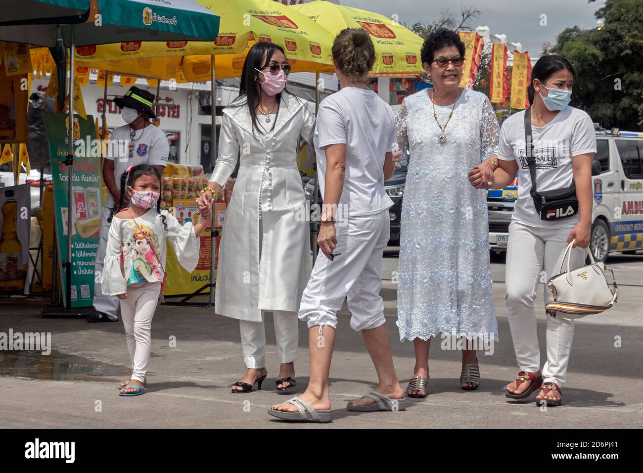 Thailand Family of women featuring four generations and all dressed in white and linked arms whilst walking together outside. Southeast Asia Stock Photo