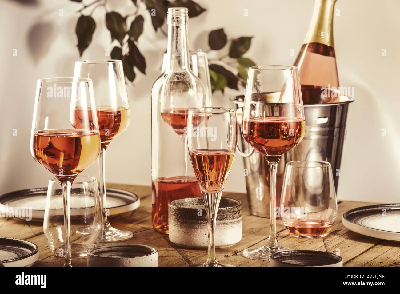 Rose wine glasses and bottles on table served for festive dinner party
