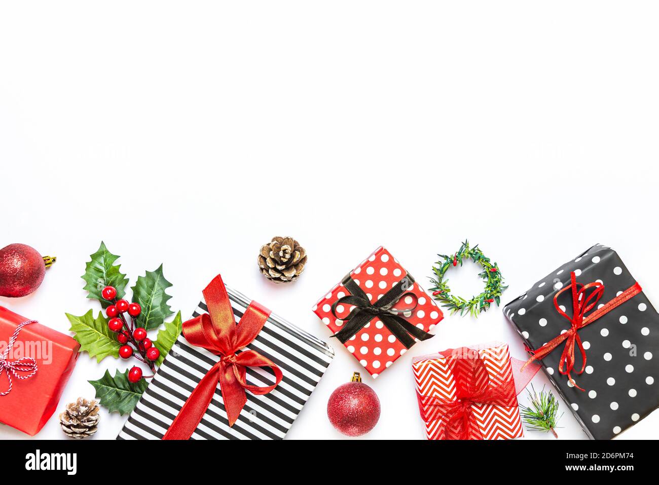 Gift boxes wrapped in striped and dotted black and white and red paper over white background. Christmas presents and ornament preparation. Copy space. Stock Photo
