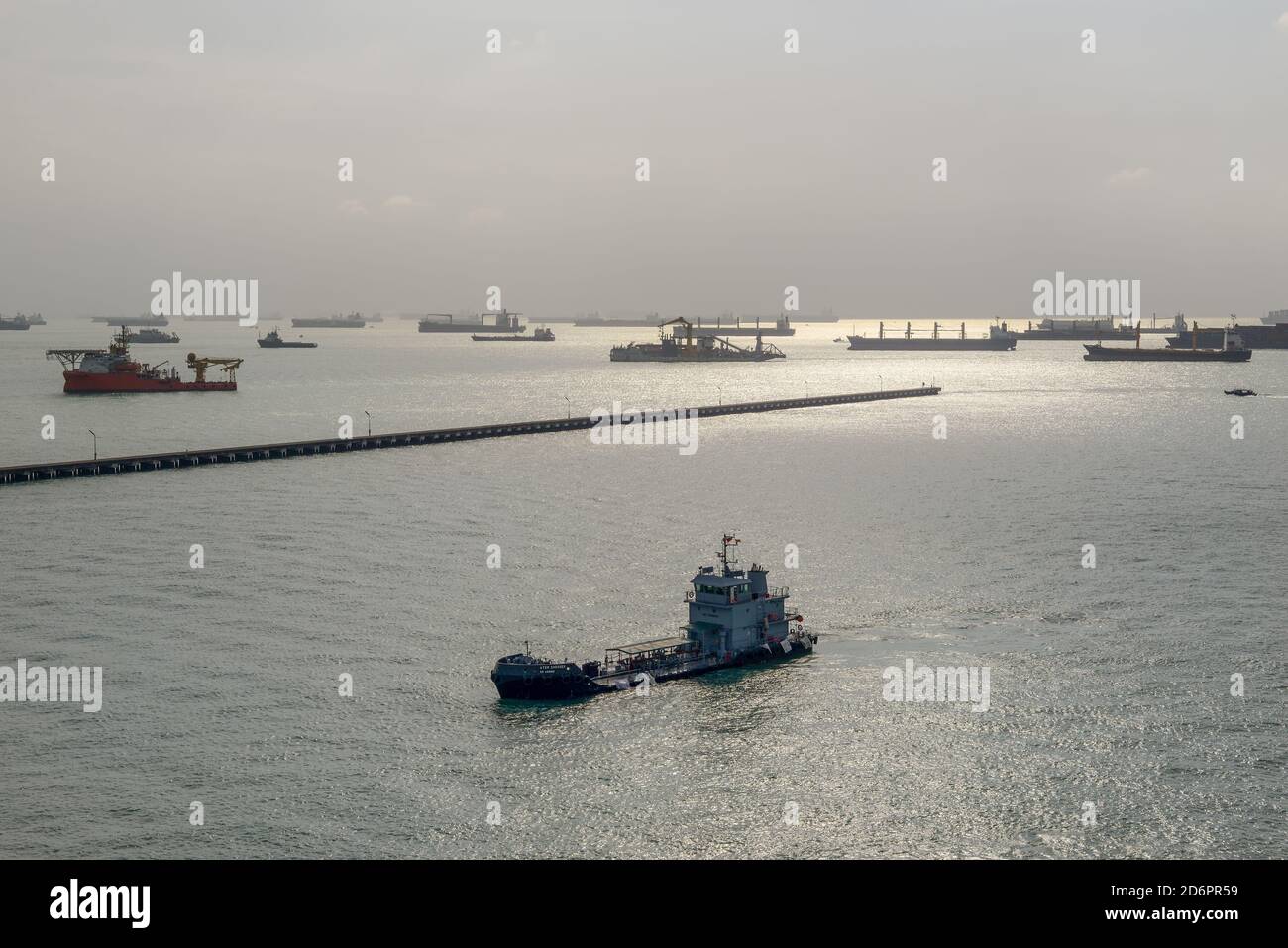 Singapore - December 3, 2019: Large collection of commercial cargo ships waiting at the anchorage just off the coast of Singapore in backlight. Stock Photo