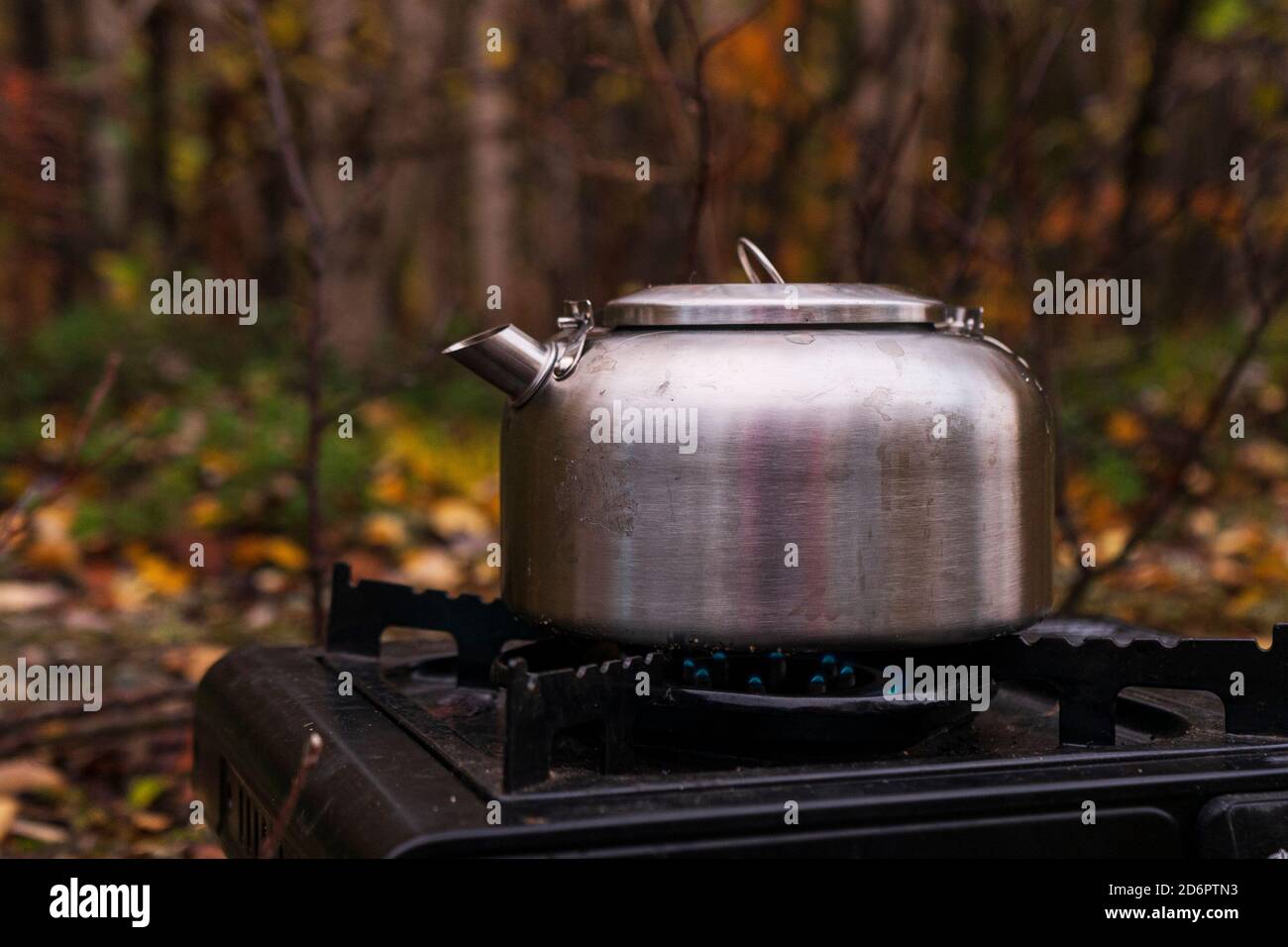 tourist metal silver teapot standing on a portable gas stove in nature