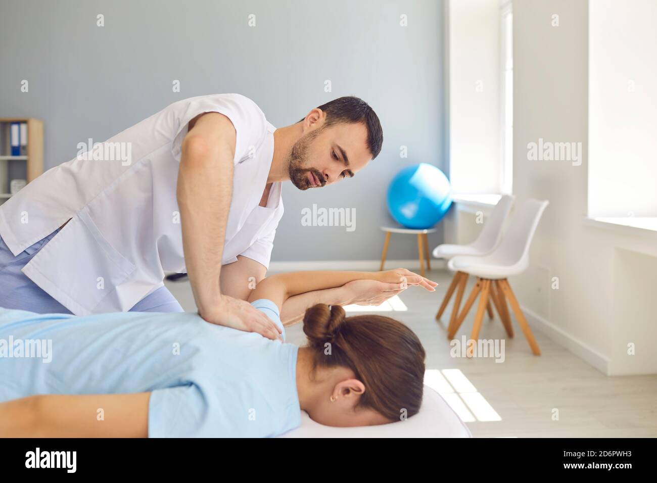 Young doctor specialist curing client's back and shoulders in modern ...