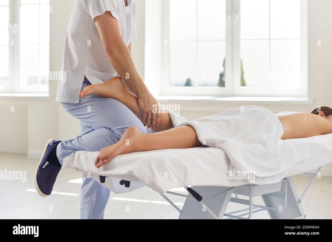 Physiotherapist or professional masseur massaging young woman's calf muscle in health center Stock Photo