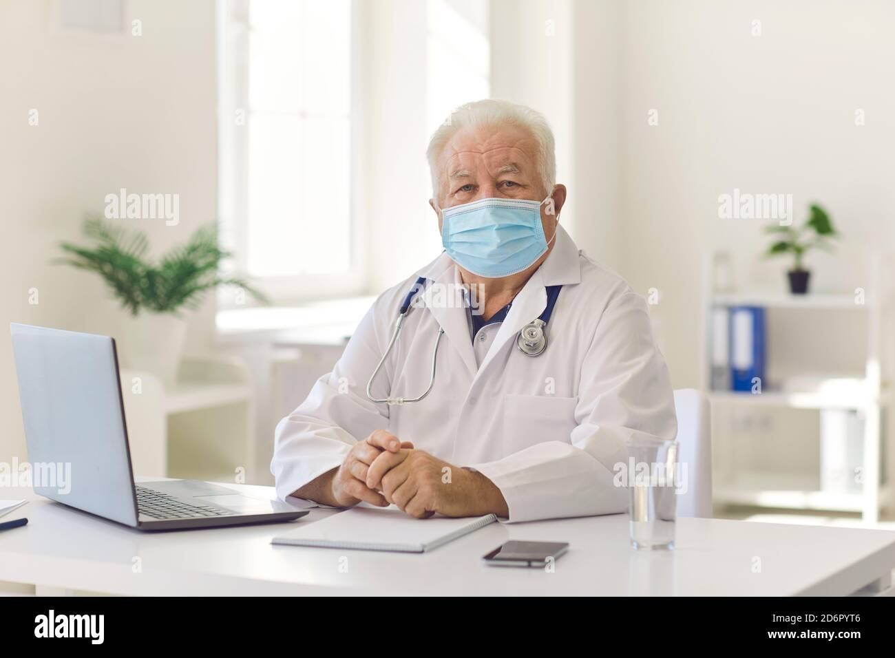 Senior experienced doctor in uniform sitting near laptop during videocall and online meeting Stock Photo