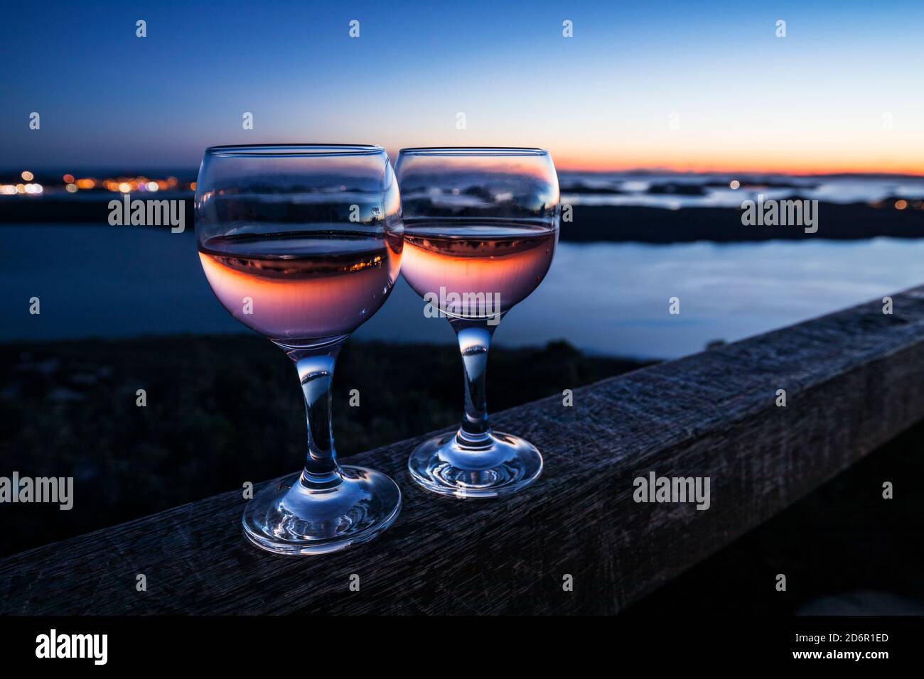 Two glasses of wine standing on the fence at sunset Stock Photo