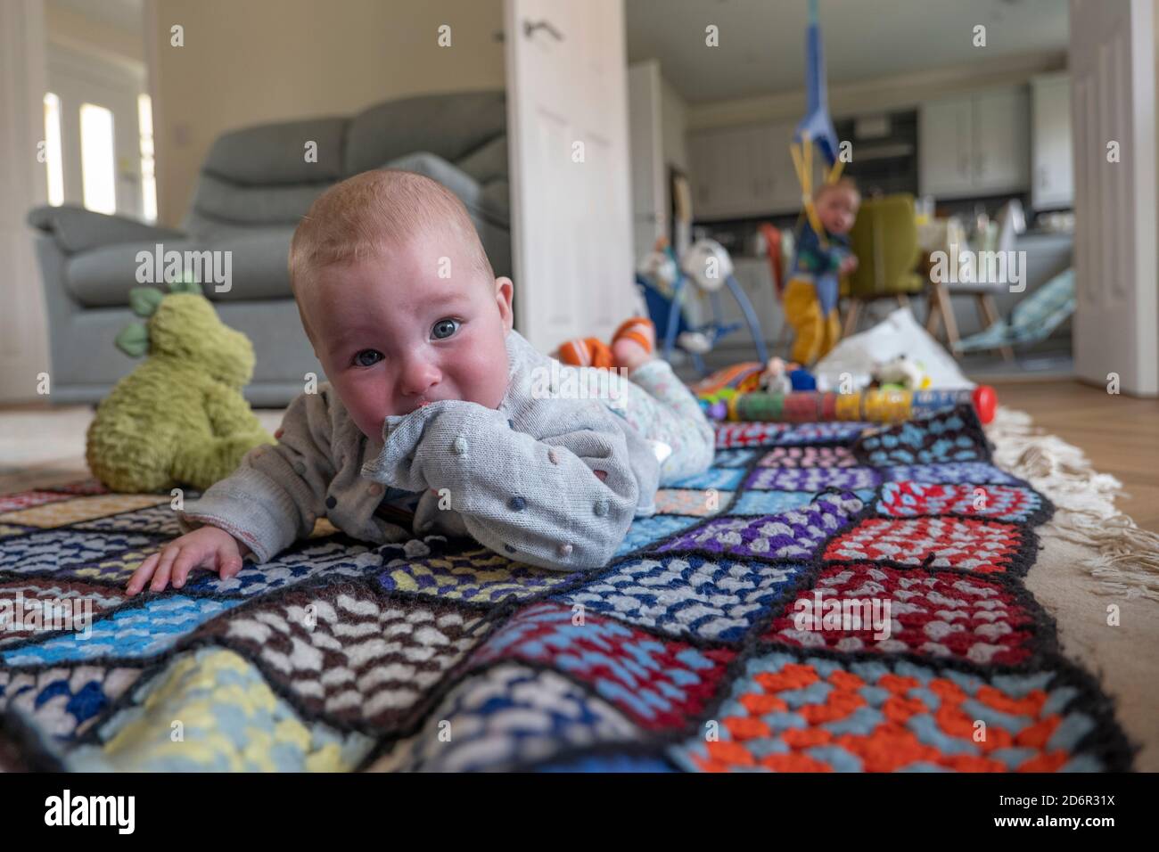 Baby girl laying on a colourful rug at home. Photo by Sam Mellish Stock Photo