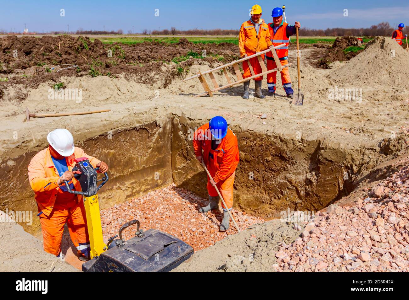 Workers are compacting gravel using vibration plate compactor machine