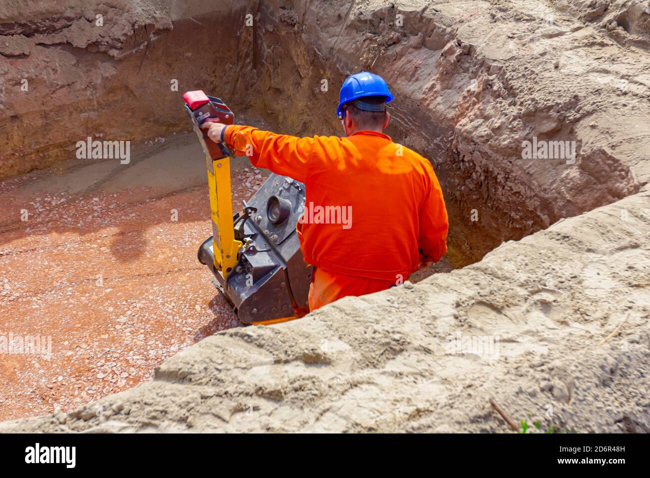 Worker is compacting gravel with vibration plate compactor machine in