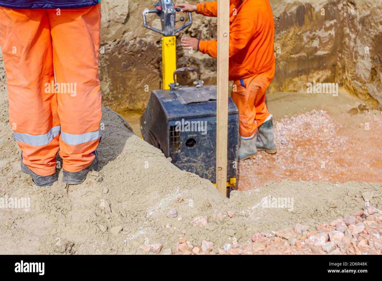 Worker is compacting gravel with vibration plate compactor machine in
