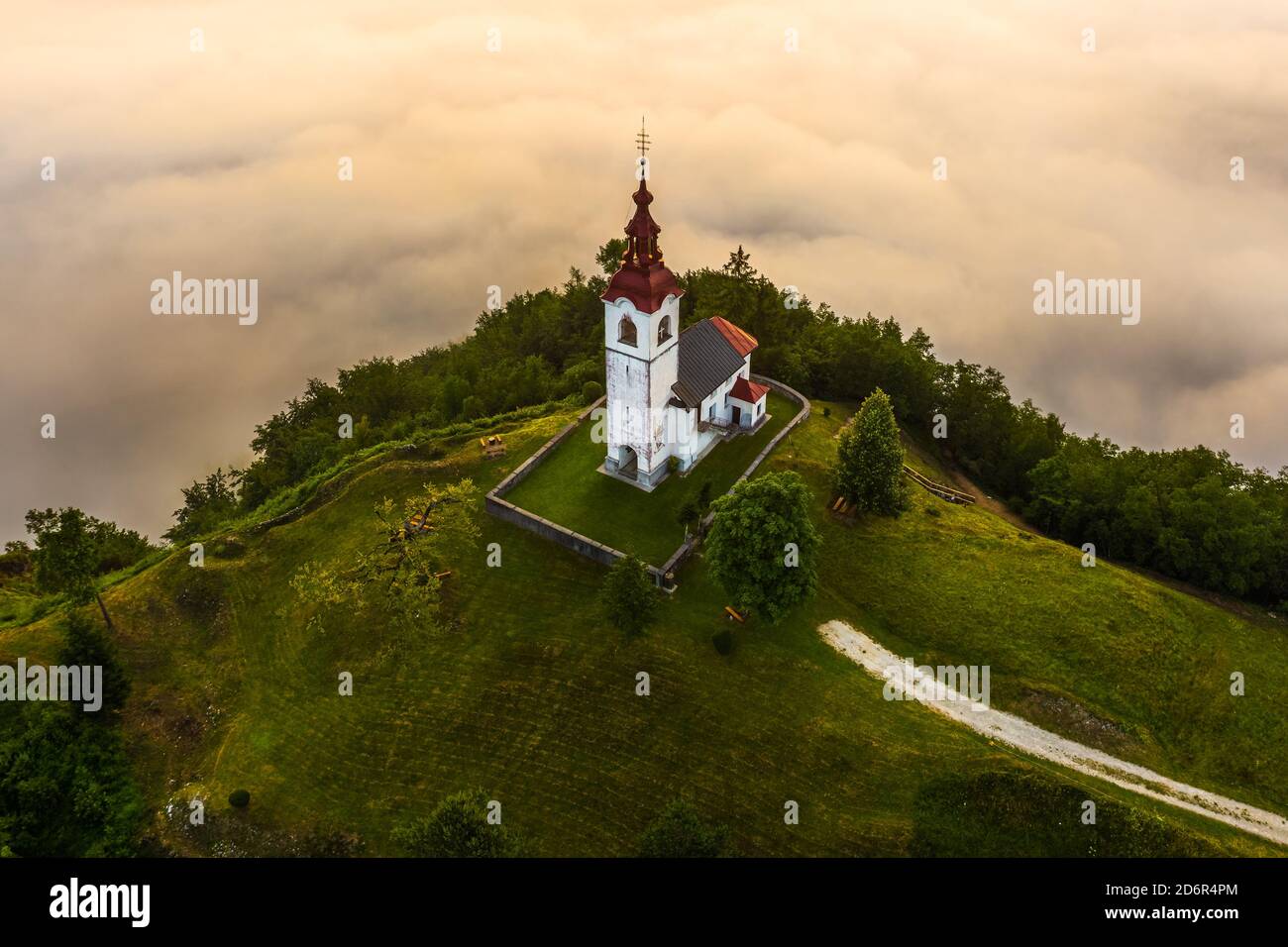 Sebrelje, Slovenia - Aerial drone view of the beautiful hilltop church of St.Ivan (Sv. Ivan Cerkev) at sunrise with huge morning fog bellow the valley Stock Photo