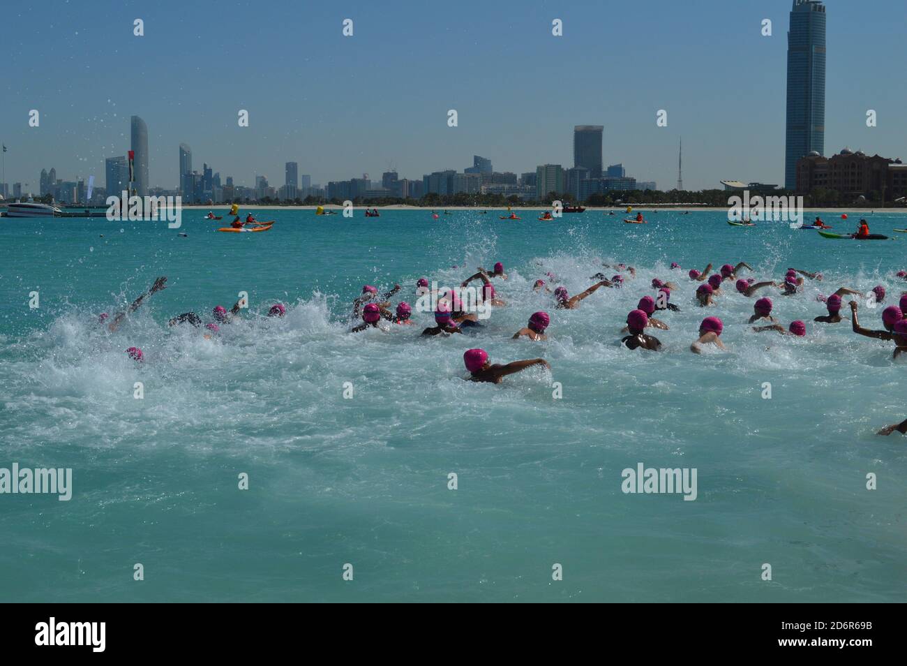 Abu Dhabi, UAE 2015. Children swimming in open sea with the city line seen behind Stock Photo
