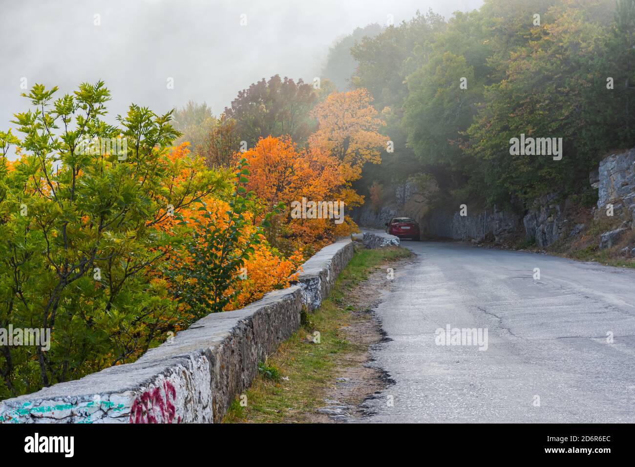 Autumn mountain road with a red car. Red Mazda cx 6 on the background of the autumn landscape. Serpentine on the ascent to the mountain AI-Petri Yalta Stock Photo
