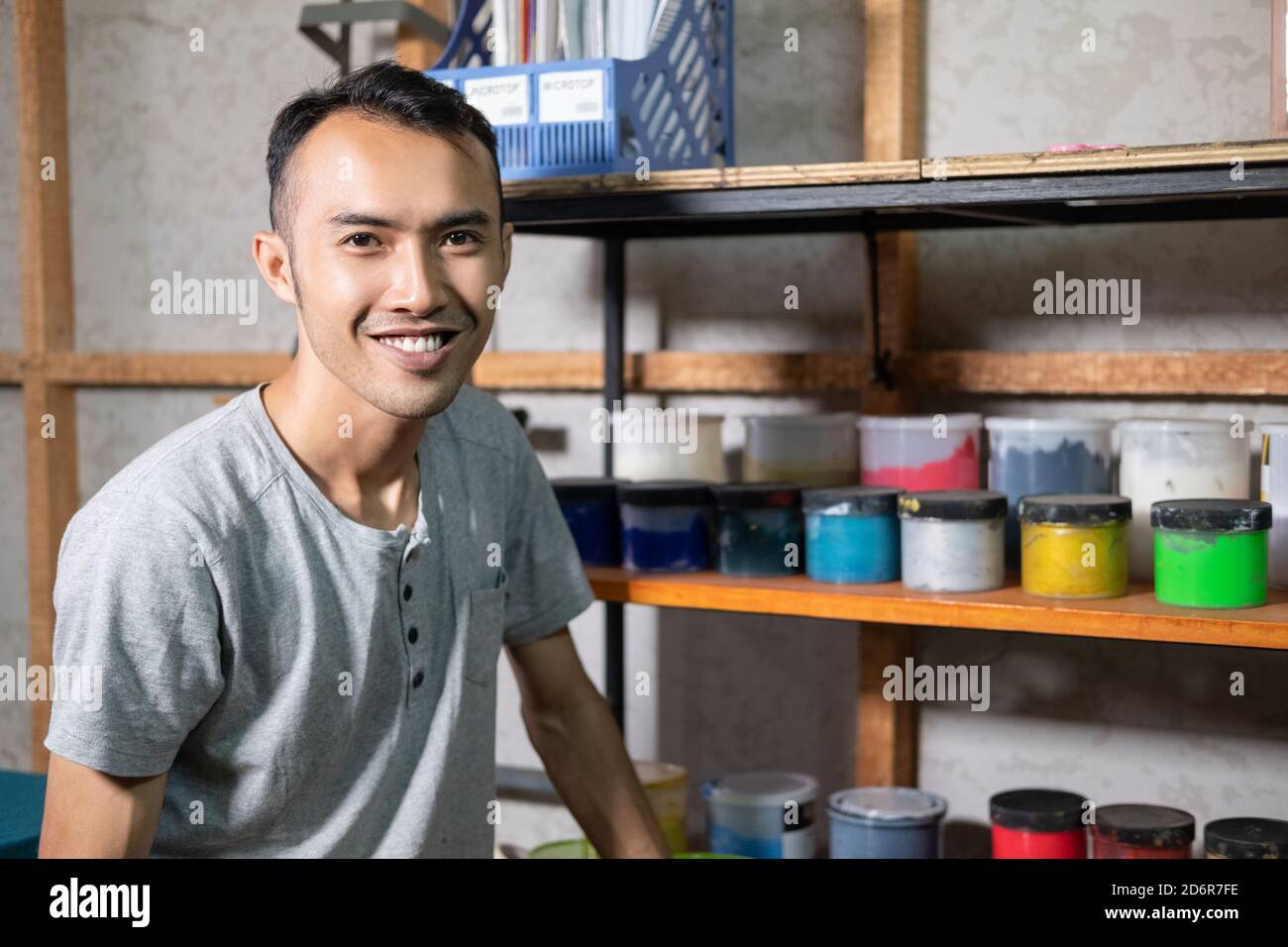 Asian men smile while sitting in front of the screen printing dye