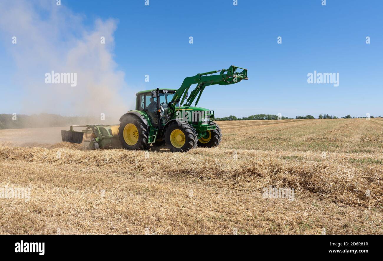 Tractor with dust cloud on a stubble field Stock Photo