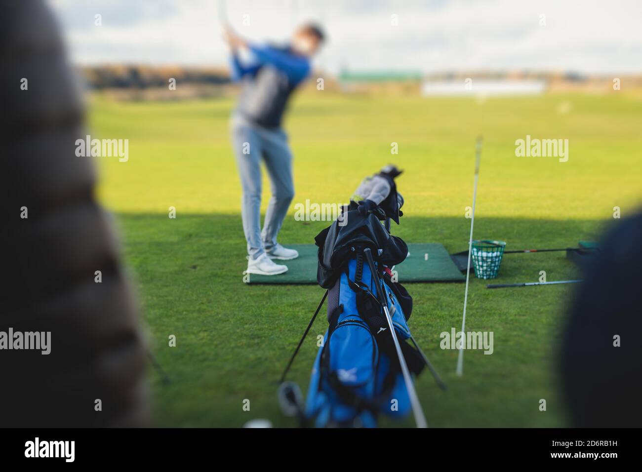 Group of golfers practicing and training golf swing on driving range