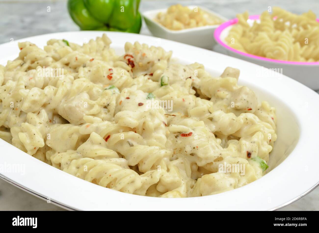 Creamy White Sauce Chicken Pasta along with the ingredients beside. Stock Photo