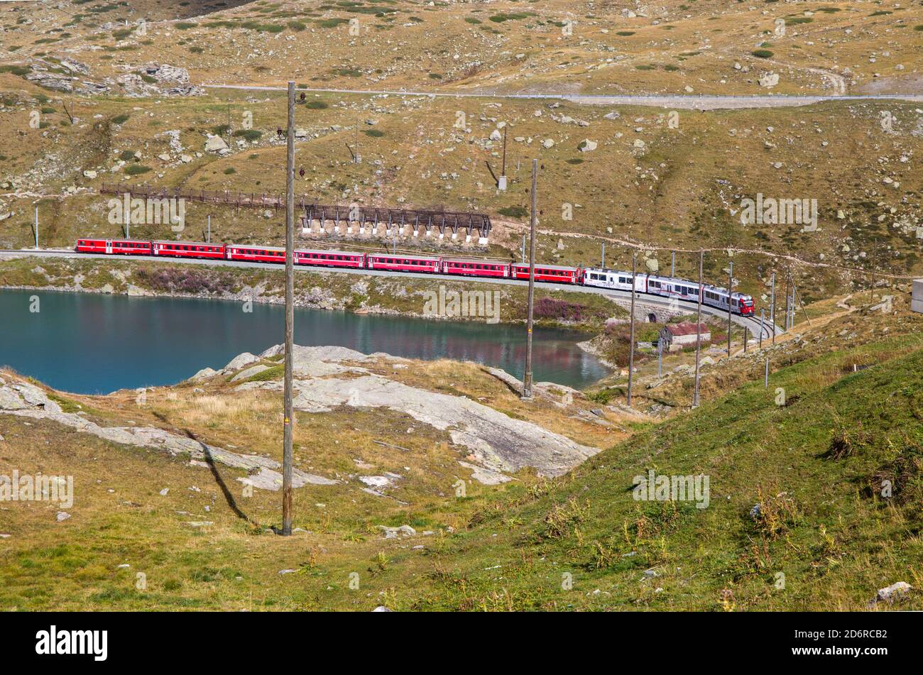The typical red Bernina Express train at Bernina Pass between Italy and Switzerland in summertime. Stock Photo