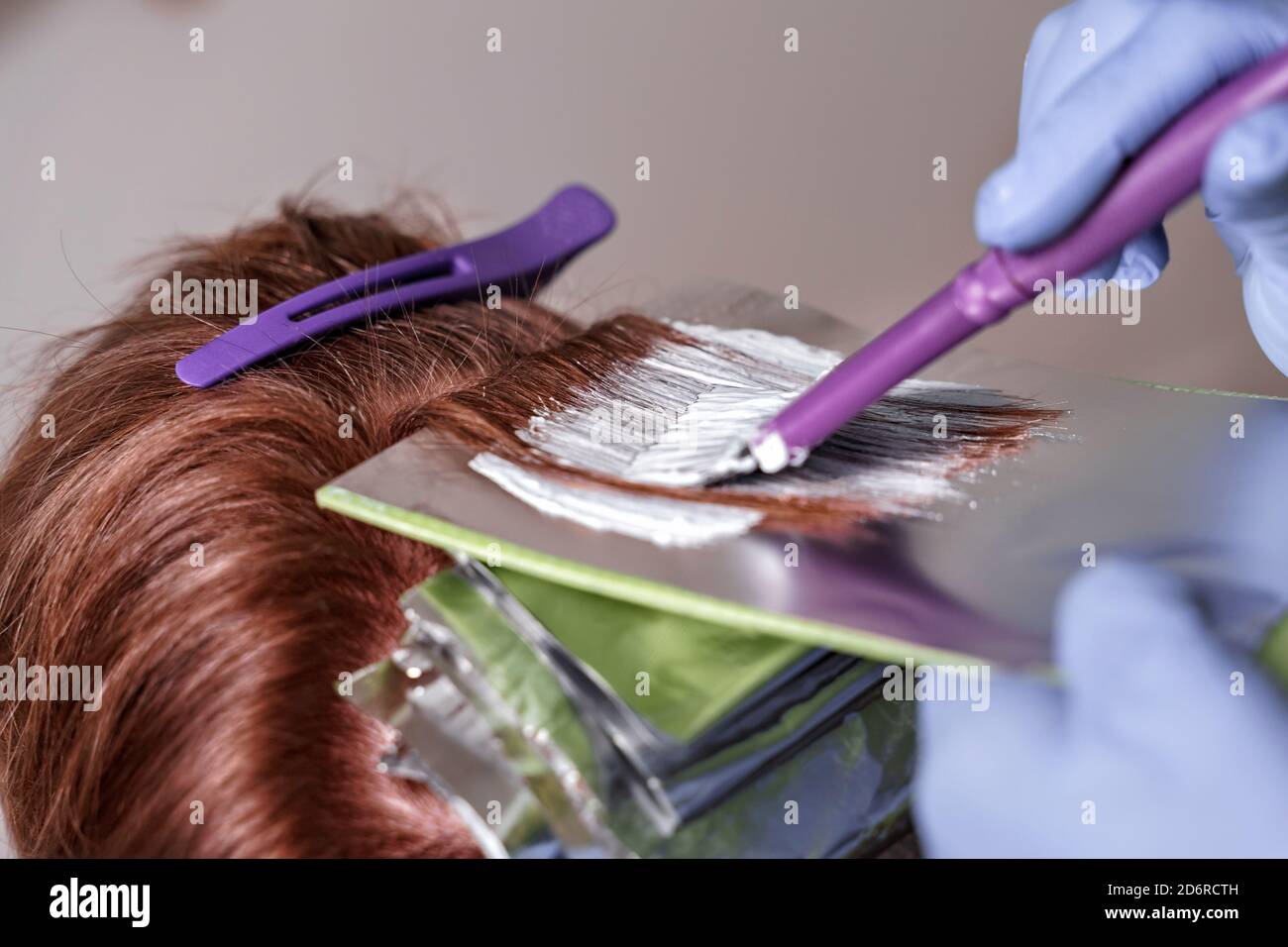 the process of dyeing red hair with foil. the master applies the composition with a brush to the
