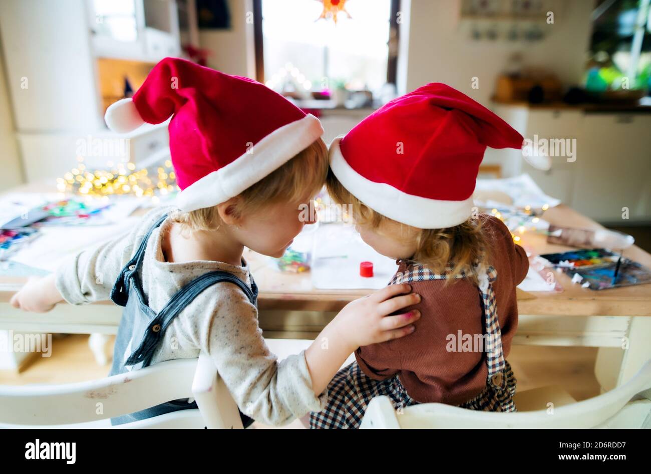 Rear view of small girl and boy indoors at home at Christmas, having fun when painting. Stock Photo