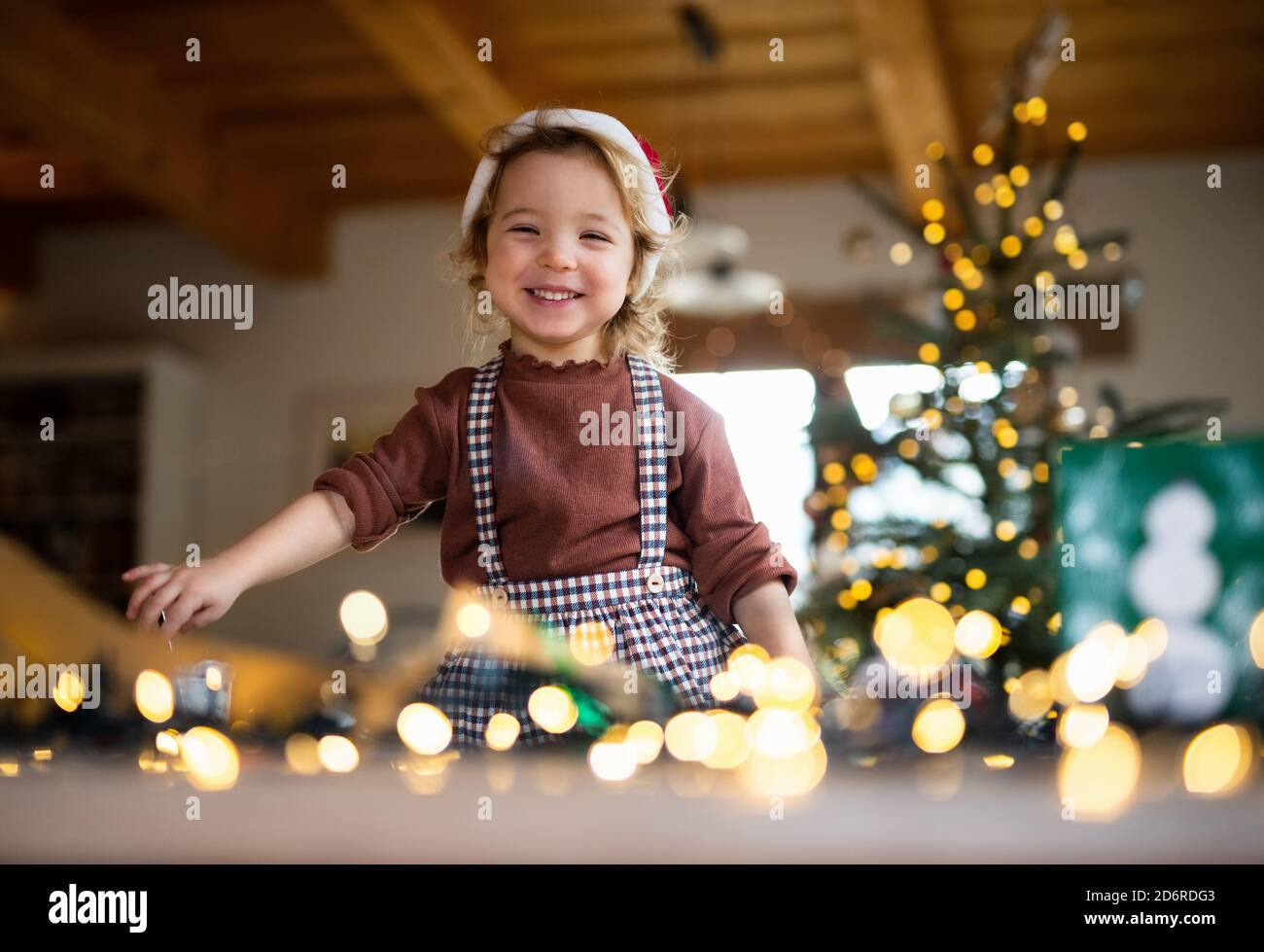 Portrait of small girl indoors at home at Christmas, laughing. Stock Photo