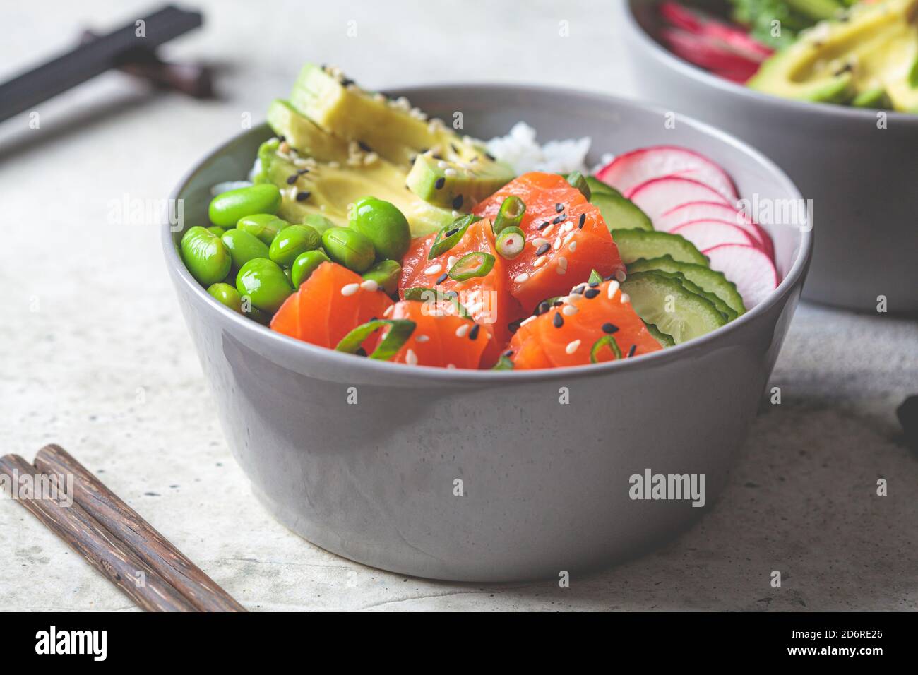 Poke bowl with salmon, rice, avocado, edamame beans, cucumber and radish in a gray bowl