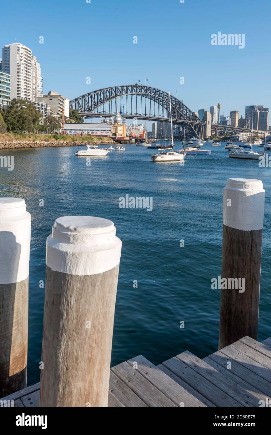 With the Harbour Bridge as a background, a timber wharf and pylons in late afternoon sun on Lavender Bay, Sydney Harbour, New South Wales, Australia Stock Photo
