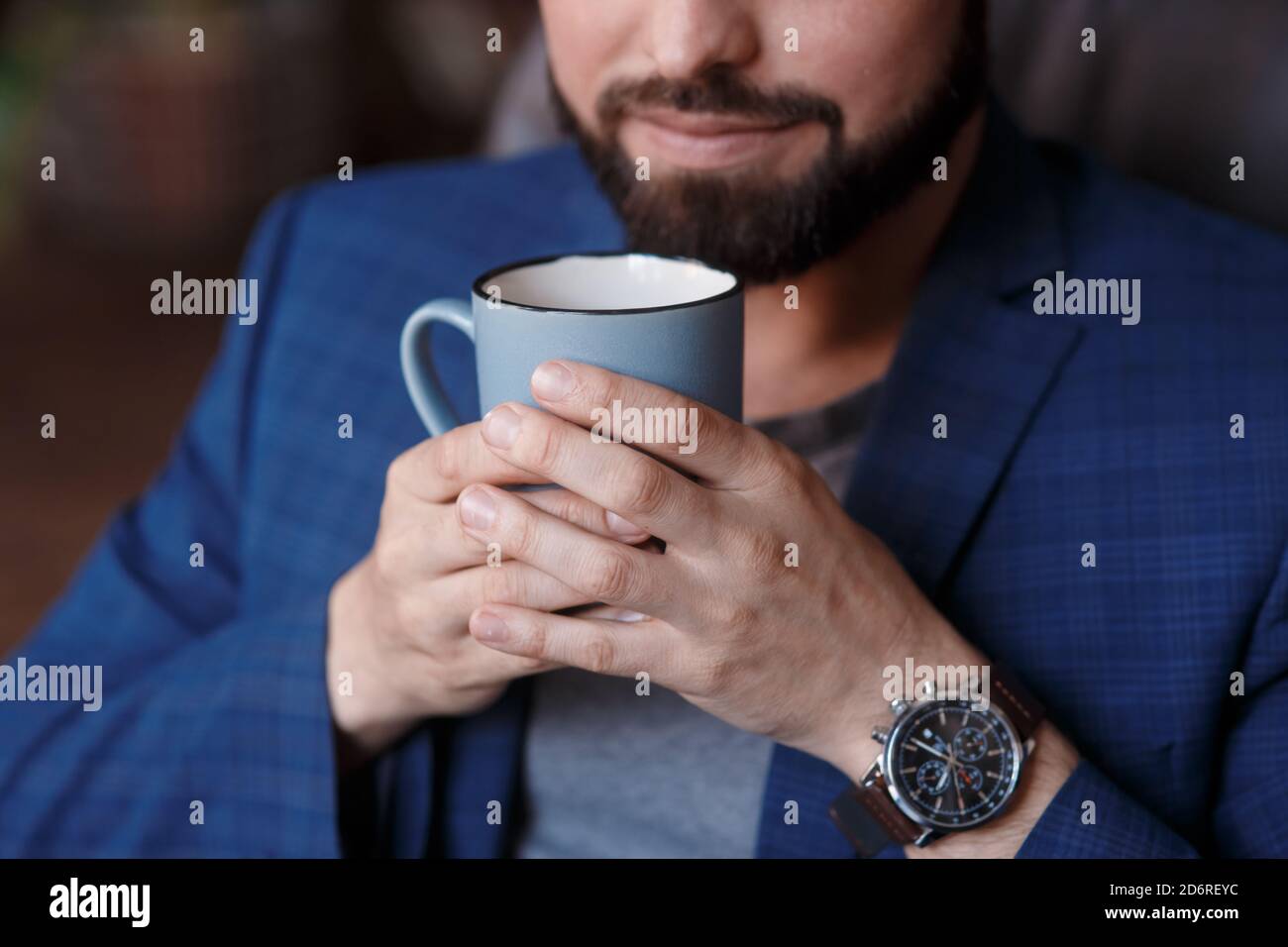 Close-up hand of young smiling businessman in formal wear holding cup ...